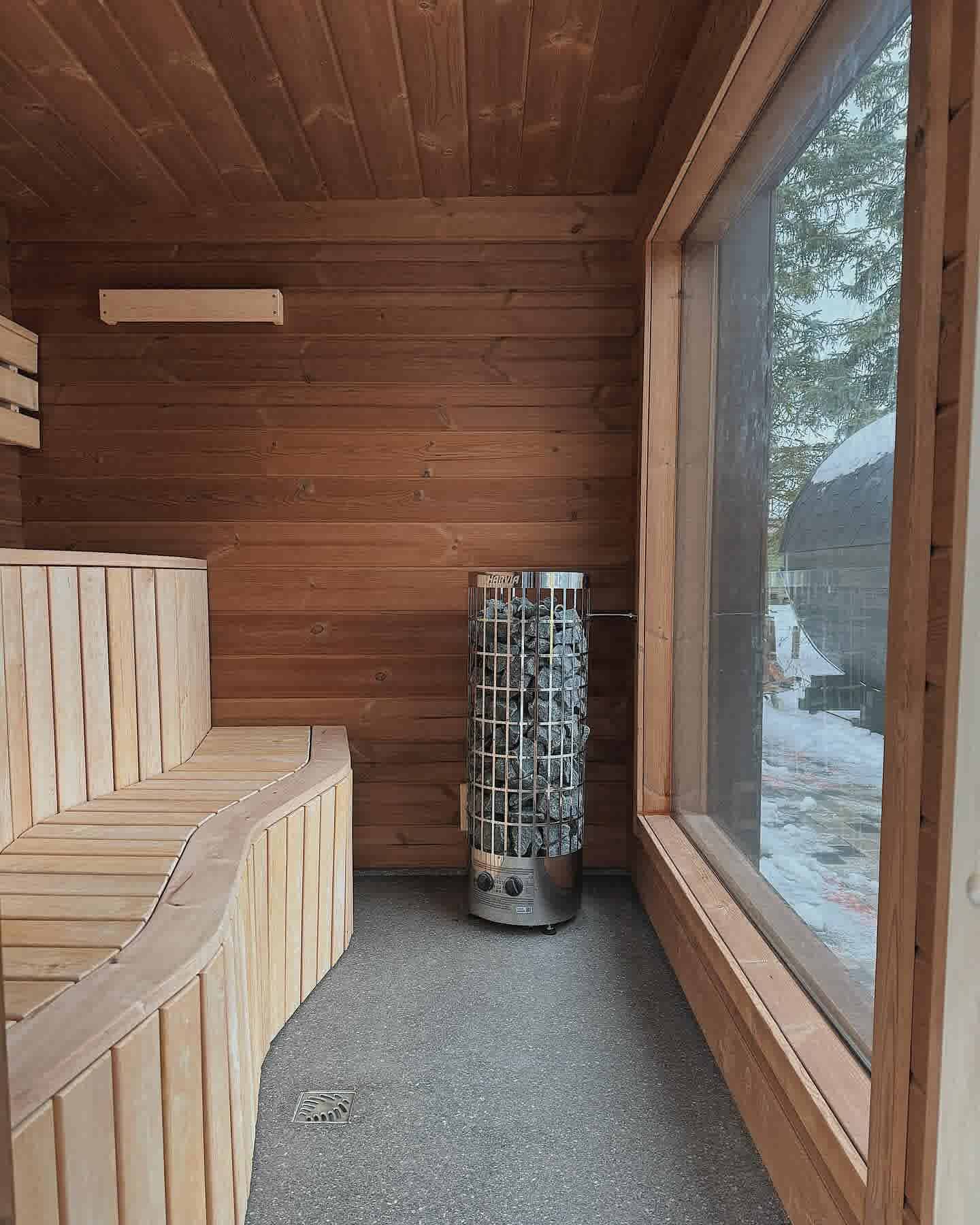 Inside a Terra Sauna cube model showing the large floor-to-ceiling window and premium Harvia heater.