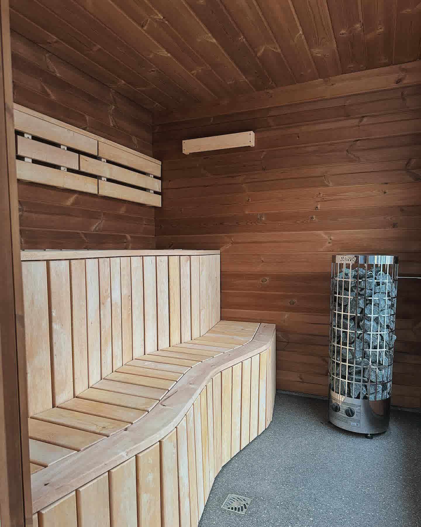Modern interior of The Cubus sauna featuring wave-style ergonomic benches and a Harvia tower electric heater.